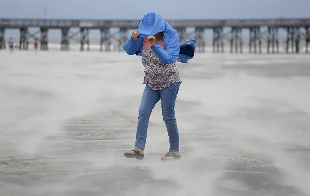 Marian Rivera covers her face from the strong wind and blowing sand as Tropical Storm Florence approaches the Isle of Palms, S.C., Friday, September 14, 2018. (Photo by Mic Smith/AP Photo)