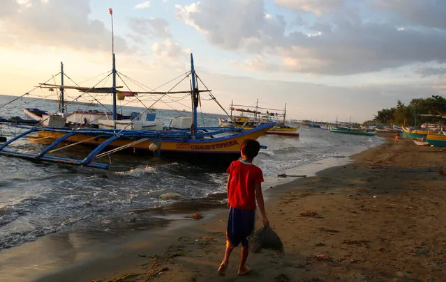 A walks past the fishing boats that just returned from disputed Scarborough Shoal, as they are docked at the coastal village of Cato in Infanta, Pangasinan in the Philippines, October 31, 2016. (Photo by Erik De Castro/Reuters)