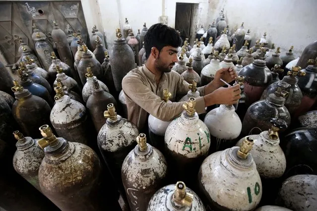 A man refills oxygen cylinders as demand for Oxygen supplies rises due to increasing COVID-19 patients, in Peshawar, Pakistan, 05 May 2021. Pakistan's Supreme Court on 05 May ordered the government to fix the price of oxygen cylinders amid the worsening coronavirus situation in the country. Pakistan Prime Minister Imran Khan ruled out a nationwide lockdown for the time being but sought the army's help in enforcing anti-coronavirus rules, including the use of face masks and implementing social distancing measures. (Photo by Bilawal Arbab/EPA/EFE)