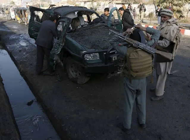 Afghan security personnel stand next to a damaged police vehicle after a blast near the Pakistani consulate in Jalalabad, Afghanistan January 13, 2016. (Photo by Reuters/Parwiz)