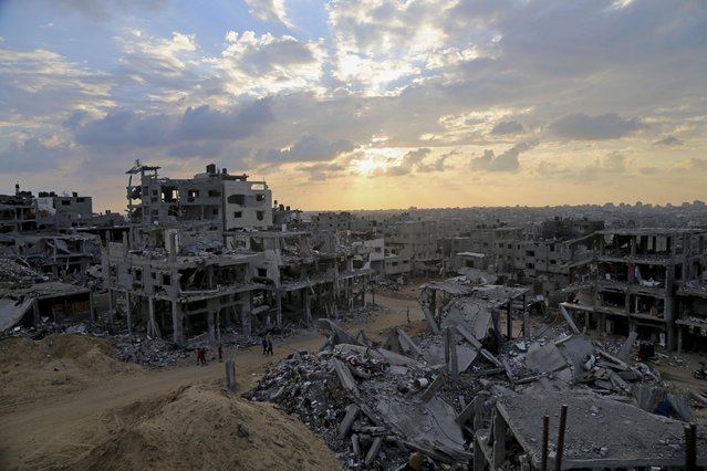 In this October 12, 2014 file photo, Palestinians walk between the rubble of a destroyed building in Shijaiyah neighborhood of Gaza City in the northern Gaza Strip. (Photo by Adel Hana/AP Photo)