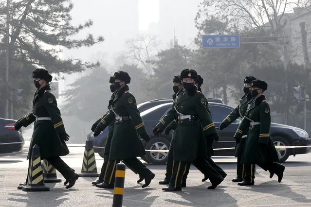Chinese paramilitary policemen wearing masks for protection against pollution march as the capital city is shrouded by smog in Beijing, Monday, December 19, 2016. Chinese cities are limiting the number of cars on roads and have temporarily shut down factories to cut down pollution during a national “red alert” for smog. (Photo by Andy Wong/AP Photo)
