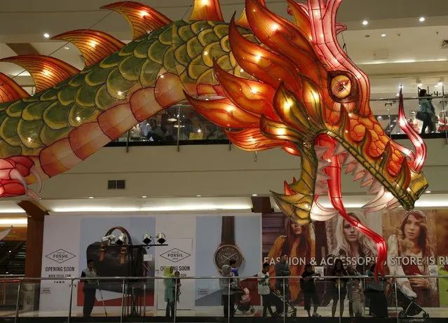 People stand near a dragon decoration for the upcoming Chinese Lunar New Year celebrations at Pondok Indah Mall in Jakarta, Indonesia February 6, 2016. (Photo by Reuters/Beawiharta)