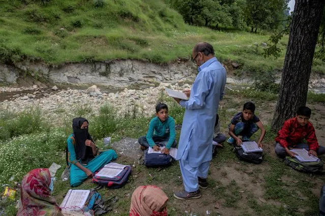 Kashmiri students listen to their teacher Ghulam Hassan, during open air community classes in Tangmarg area northwest of Srinagar, Indian controlled Kashmir, Wednesday, August 4, 2021.Government teachers are holding community classes in areas where students do not have access to internet service and remain unavailable for online teaching since June this year. Schools in Indian controlled Kashmir continue to remain closed for onsite teaching in view of the COVID-19 pandemic. (Photo by Dar Yasin/AP Photo)