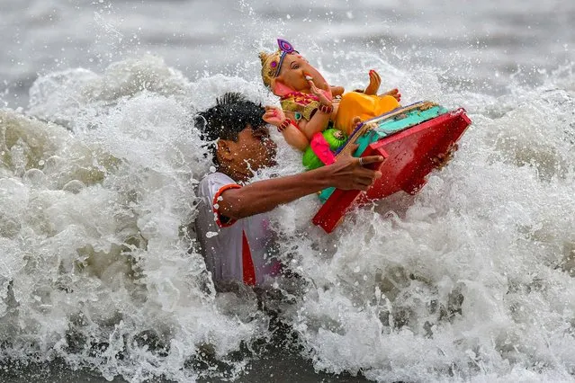 A volunteer carries an idol of the elephant-headed Hindu god Ganesha for immersion in the Arabian sea on the fifth day of the ten-day-long Ganesh festival in Mumbai on September 4, 2022. (Photo by Punit Paranjpe/AFP Photo)