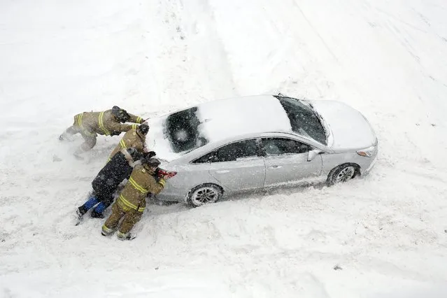 Firefighters help push a car stuck in snow during a winter storm in Ottawa, Canada, February 16, 2016. (Photo by Chris Wattie/Reuters)