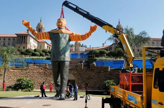A crane places a statue of former South African president Nelson Mandela into position at the Union buildings in Pretoria, South Africa,Friday, December 13, 2013. The body of Mandela will lay in state for the third and final day on Friday ahead of his funeral in Qunu on December 15. (Photo by Tsvangirayi Mukwazhi/AP Photo)