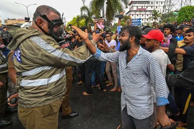A protestor shouts as a policeman stands guard during an anti-government demonstration by the university students demanding the release of their leaders, in Colombo on October 18, 2022. (Photo by Ishara S. Kodikara/AFP Photo)