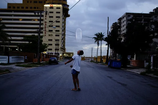 Arturo Perez, 14, plays on the street with a condom in Havana, Cuba, August 27, 2018. (Photo by Alexandre Meneghini/Reuters)