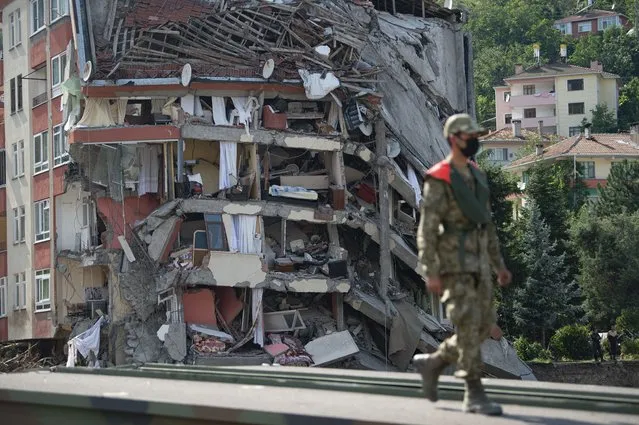 A soldier walks on a temporary bridge set up by military in Bozkurt town of Kastamonu province, Turkey, Sunday, August 15, 2021, after flooding. Turkey sent ships to help evacuate people and vehicles from a northern town on the Black Sea that was hard hit by flooding, as the death toll in the disaster rose Sunday to at least 62 and more people than that remained missing. (Photo by AP Photo/Stringer)