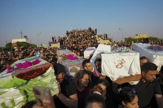 Friends and relatives attend the funeral of people who died in a fire during a wedding ceremony in Hamdaniya, Iraq, Wednesday, September 27, 2023. A fire that raced through a hall hosting a Christian wedding in northern Iraq has killed around 100 people and injured 150 others, and authorities warn the death toll could rise. (Photo by Hadi Mizban/AP Photo)