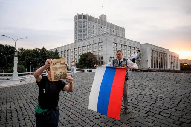 A man holds a Russian flag during the 30th anniversary of the failed August 1991 coup outside the Russian Government building in Moscow on August 19, 2021. Russia marks on August 19-22, 2021, the 30th anniversary of the abortive 1991 coup against then Soviet president Mikhail Gorbachev. Tanks rolled through Moscow towards the Russian White House, where Boris Yeltsin, leader of the Soviet-era Russian republic at the time, gathered his supporters after denouncing the coup from the roof of a tank, what resulted later a collapse of the Soviet empire. (Photo by Dimitar Dilkoff/AFP Photo)
