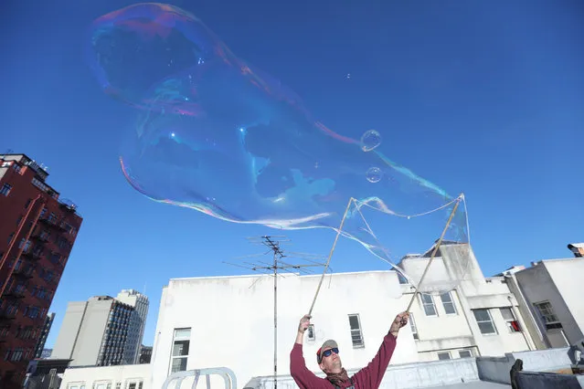 Kurth Reis makes a giant bubble on a rooftop in San Francisco, California, U.S. on June 15, 2021. (Photo by Nathan Frandino/Reuters)