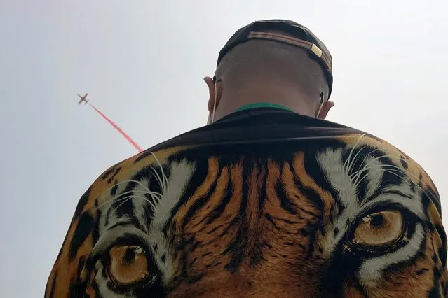 A man watches Chinese People's Liberation Army (PLA) Air Force Red Falcon aerobatic team perform at the China International Aviation and Aerospace Exhibition, or Airshow China, in Zhuhai, Guangdong province, China on September 28, 2021. (Photo by Aly Song/Reuters)