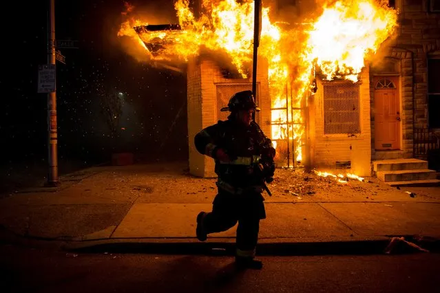 Baltimore firefighters attack a fire in a convenience store and residence during clashes after the funeral of Freddie Gray in Baltimore, Maryland in the early morning hours of April 28, 2015. (Photo by Eric Thayer/Reuters)