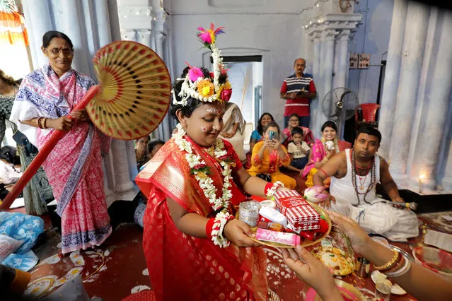 An Indian girl Isha Bannerje (C) dresses up as Goddess Durga during Kumari Puja ritual as a part of the Durga Puja Hindu festival, at Nandi Bari far North of Kolkata, Eastern India, 14 October 2021. During the Kumari Puja, devotees worship a girl aged between six and twelve, symbolizing the Kanya Kumari (virgin) form of the Goddess Durga Devi. Hindu devotees believe that the Kanya is a living embodiment of the goddess Durga. (Photo by Piyal Adhikary/EPA/EFE)