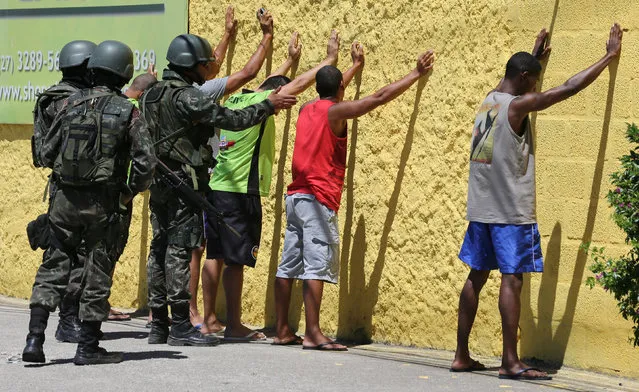 Army soldiers check people, during a military police strike over wages, while patrolling the streets of Vila Velha, Espirito Santo, Brazil, February 11, 2017. (Photo by Paulo Whitaker/Reuters)