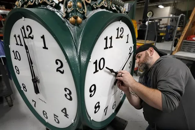Clock technician Dan LaMoore, of Woonsocket, R.I., adjusts clock hands on a large outdoor clock under construction at Electric Time Company, Tuesday, November 2, 2021, in Medfield, Mass. Daylight Saving Time ends Sunday, Nov. 7, 2021, at 2:00 a.m., when clocks are set back one hour. (Photo by Steven Senne/AP Photo)
