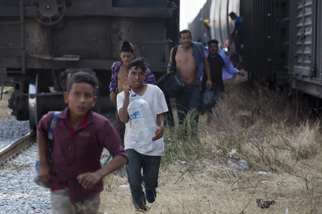 Central American migrants run for a parked train during their journey toward the US-Mexico border, in Ixtepec, Oaxaca state, Mexico, Tuesday, April 23, 2019. The once large caravan of about 3,000 people was essentially broken up by an immigration raid on Monday, as migrants fled into the hills, took refuge at shelters and churches or hopped passing freight trains. (Photo by Moises Castillo/AP Photo)