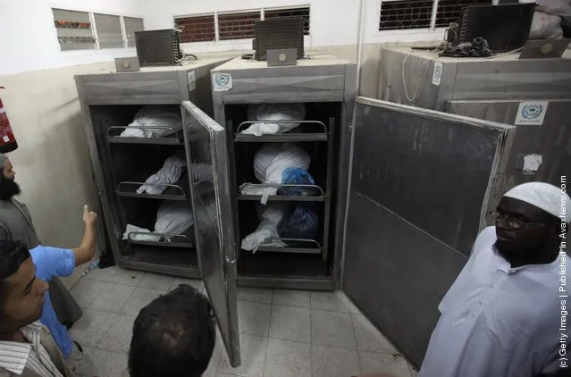 Palestinians stand in the morgue next to the bodies of six militants killed in an Israeli airstrike