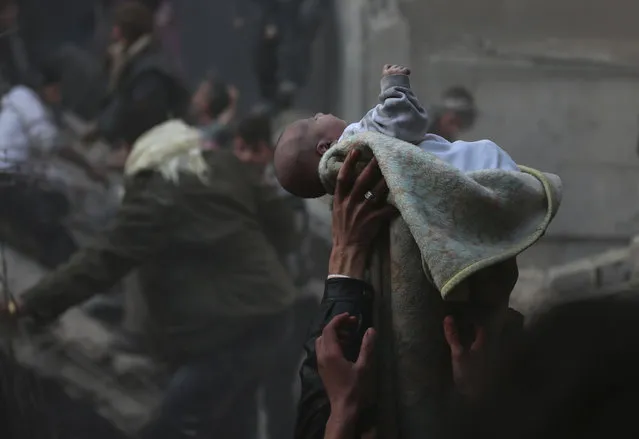Men hold up a baby saved from under rubble, who survived what activists say was an airstrike by forces loyal to Syrian President Bashar al-Assad in the Duma neighborhood of Damascus January 7, 2014. (Photo by Bassam Khabieh/Reuters)