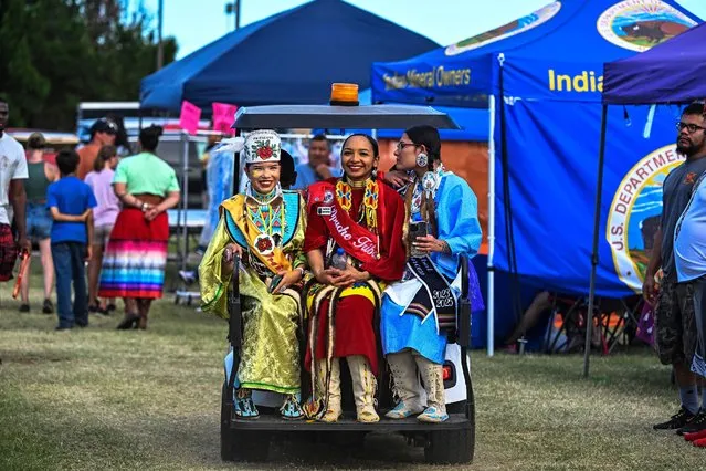 Women in indigenous costumes sit in a gold cart during a cultural meeting at the Comanche Nation fairgrounds in Lawton, Oklahoma on September 30, 2023. After Alaska, Oklahoma is the US state with the most Native Americans of voting age – 12 percent of the population, according to government census statistics. While Rock The Native Vote, an association that encourages the Native American community to go to the polls, has seen an increase in the number of Native Americans registering to vote since the 2020 presidential election, overall voter turnout remains low. (Photo by Chandan Khanna/AFP Photo)