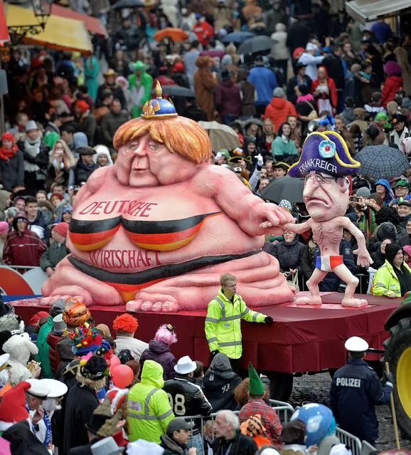 A carnival float depicting a fat chancellor Angela Merkel, left, representing  the growing German economy, and a slim French president Francois Hollande during the traditional carnival parade in Duesseldorf, western Germany, on Monday, March 3, 2014. The foolish street spectacles in the carnival centers of Duesseldorf, Mainz and Cologne, watched by hundreds of thousands of people, are the highlights in Germany's carnival season on Rose Monday. (Photo by Martin Meissner/AP Photo)