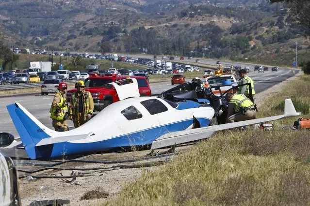 Emergency personnel investigate the scene of plane crash, Saturday, April 2, 2016 in Fallbrook, Calif. A small plane crashed on a Southern California freeway Saturday and struck a car, killing one person and injuring five others, authorities said. (Photo by Don Boomer/The San Diego Union-Tribune via AP Photo)