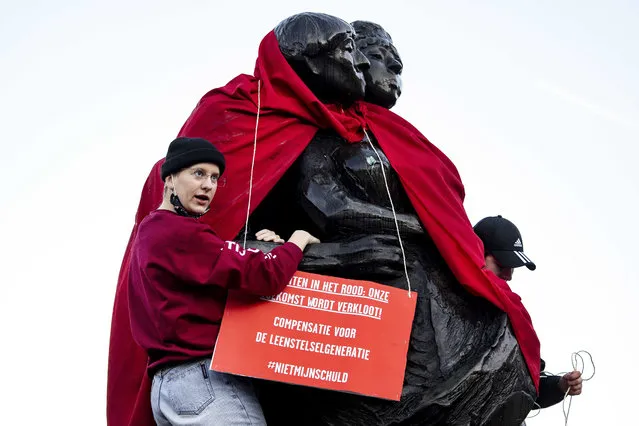 Students dress the Bredero monument with red clothes in Amsterdam, The Netherlands, 16 December 2021. The action is aimed as a protest against the lack of proper compensation for the loan system generation in the presented coalition agreement. (Photo by Ramon van Flymen/EPA/EFE)
