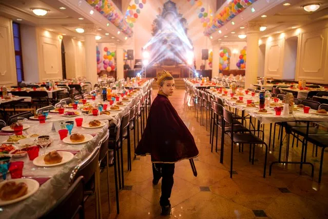 A child of the Ukrainian Jewish community, walks between tables set for Purim celebrations before a festive meal at the Great Choral Synagogue in Kyiv, Ukraine, Sunday, March 24, 2024. (Photo by Vadim Ghirda/AP Photo)