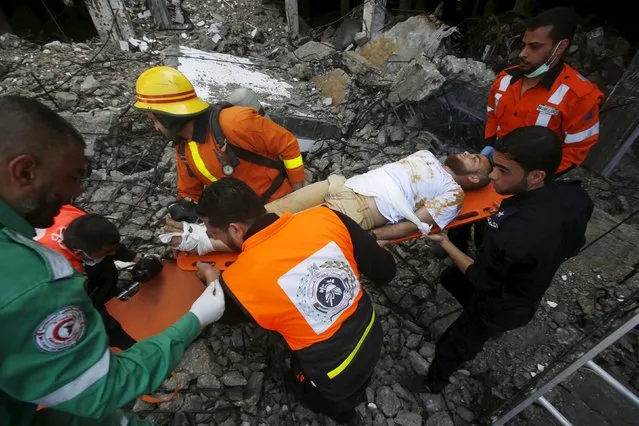 Medics and members of Palestinian Civil Defence reenact a scene simulating the evacuation of a victim during a drill, at a building destroyed during the 2014 war, in Gaza City April 19, 2016. (Photo by Suhaib Salem/Reuters)