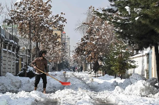 A man uses a shovel to clear snow from a street after heavy snowfall in Kabul on January 5, 2022. (Photo by Mohd Rasfan/AFP Photo)