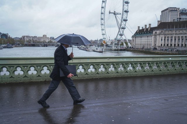 A pedestrian sheltering with an umbrella on Westminster Bridge during rain showers in London on April 9, 2024. The Met Office has issued weather warnings for wind and rain for the south and western coast of England and Wales lasting the week. (Photo by Amer Ghazzal/Alamy Live News)
