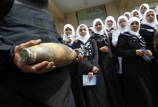 A Palestinian explosives expert loyal to the ruling Hamas movement holds a mortar shell as he explains to schoolgirls the danger of unexploded ordnance on April 7, 2014 at a school in Khan Younis in the southern Gaza. (Photo by Said Khatib/AFP Photo)