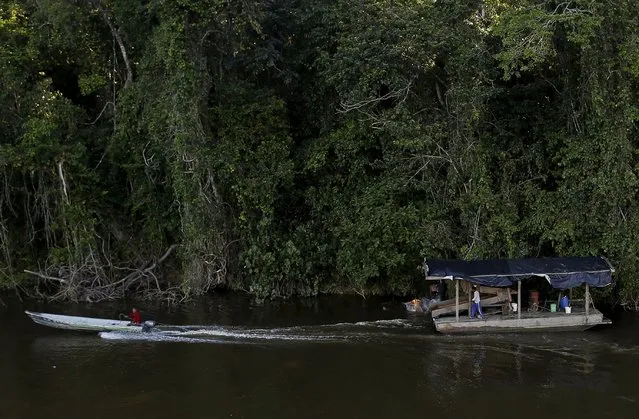 A man successfully flees in a boat next to an illegal gold dredge on the banks of Uraricoera River during Brazil’s environmental agency operation against illegal gold mining on indigenous land, in the heart of the Amazon rainforest, in Roraima state, Brazil April 15, 2016. (Photo by Bruno Kelly/Reuters)