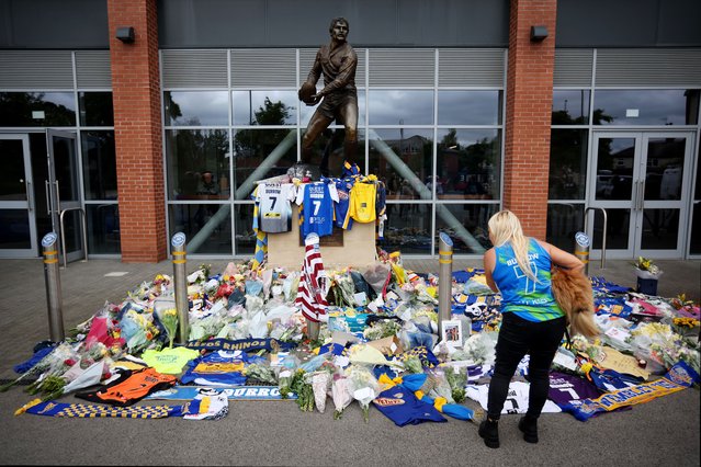 A general view as a member of the public and her dog, wearing a vest which reads “Burrow 7”, admires tributes left at the statue of former Leeds Rhinos player John Holmes as they pay their respects, in memory of ex-Leeds Rhinos and England rugby league player Rob Burrow on June 03, 2024 in Leeds, England. Rugby league legend Burrow passed away at the age of 41 following a four-and-a-half-year battle with motor neurone disease (MND). (Photo by Ed Sykes/Getty Images)