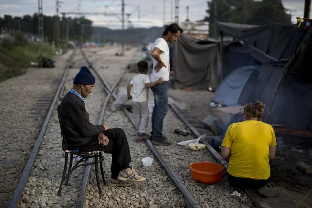 An elderly man sits on a chair among railway tracks at a makeshift refugee camp on the northern Greek border point of Idomeni, Sunday, May 15, 2016. Thousands of stranded refugees and migrants have camped in Idomeni for months after the border was closed. (Photo by Petros Giannakouris/AP Photo)