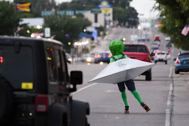 A person wearing an alien costume in a flying saucer roller skates through traffic down Main Street during the UFO Festival on July 2, 2021 in Roswell, New Mexico. The festival returns during the July 4th holiday weekend following the Covid-19 pandemic. A highly awaited US intelligence report on dozens of mysterious unidentified flying object sightings said most could not be explained, but did not rule out that some could be alien spacecraft. The report made no mention of the possibility of – or rule out – that some of the objects sighted could represent extra-terrestrial life. The military and intelligence community have conducted research on them as a potential threat. (Photo by Patrick T. Fallon/AFP Photo)