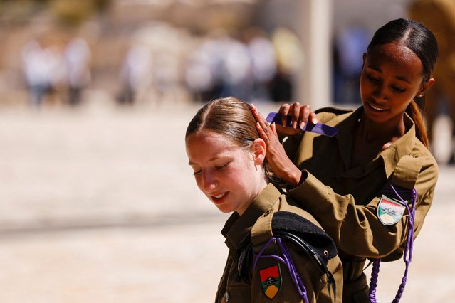 An Israeli soldier combs the hair of another soldier, on the day of a ceremony marking Israel's Memorial Day, which commemorates fallen soldiers of Israel's wars and Israeli victims of militant attacks, at the memorial site for fallen soldiers from the Armored Corps, in Latrun, Israel on April 25, 2023. (Photo by Amir Cohen/Reuters)