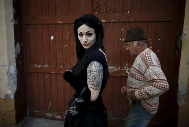 A participant of the Castle Party festival poses for picture as a man walks past in Bolkow, southwestern Poland, July 16, 2015. (Photo by Kacper Pempel/Reuters)