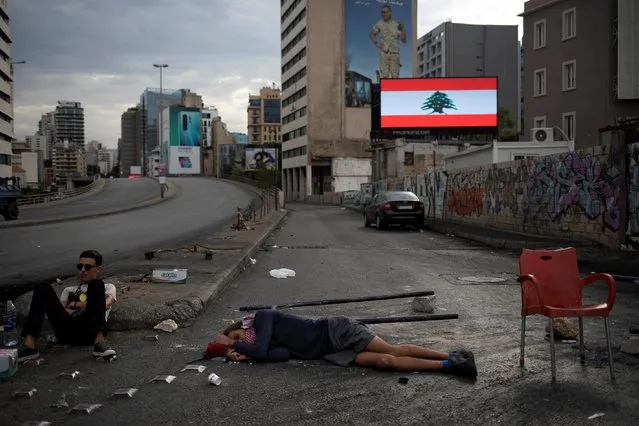 A demonstrator rests on the ground as he and other demonstrators block a highway during ongoing anti-government protests in downtown Beirut, Lebanon, October 23, 2019. (Photo by Alkis Konstantinidis/Reuters)