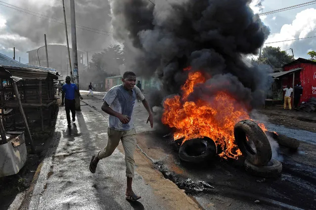 A protestor runs past a burning barricade in Kibera slum, Nairobi on May 23, 2016 during a demonstration of opposition supporters protesting for a change of leadership ahead of a vote due next years on May 23, 2016 in Nairobi. (Photo by Carl De Souza/AFP Photo)