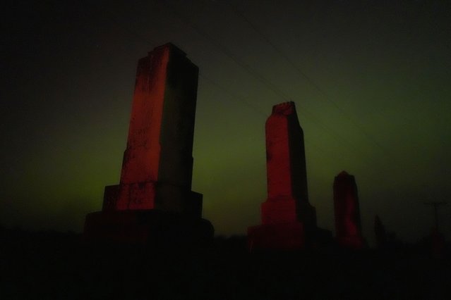 Old tombstones stand against the northern lights at a cemetery early Saturday, May 11, 2024, near Skidmore, Mo. (Photo by Charlie Riedel/AP Photo)