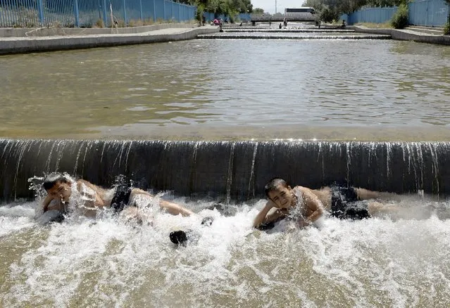 Children lie in a canal to cool off from summer heat in Urumqi, Xinjiang Uighur Autonomous Region, China, July 22, 2015. The highest temperature in the city reached 40 degrees Celsius (104 degrees Fahrenheit) on Wednesday, local media reported. (Photo by Reuters/Stringer)