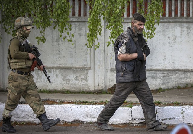 Self-proclaimed Donetsk People's Republic (DPR) militia escorts an Ukrainian serviceman as he is being evacuated from the besieged Azovstal steel plant in Mariupol, Ukraine, 17 May 2022. (Photo by Alessandro Guerra/EPA/EFE)