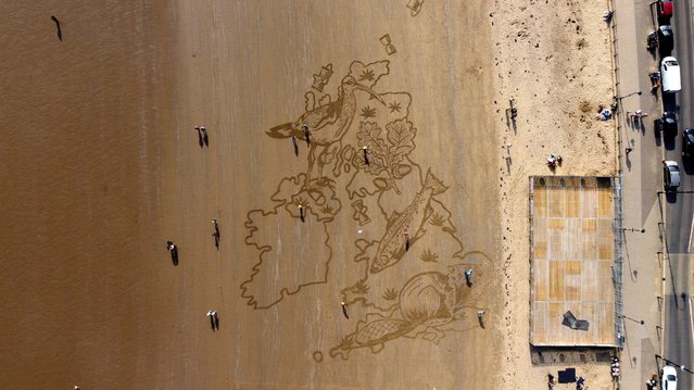 People walk past a huge sand drawing on South Bay Beach, created by Sand in Your Eyes to highlight young peoples alarm at the loss of wildlife in Scarborough, Britain, March 23, 2022. (Photo by Lee Smith/Reuters)