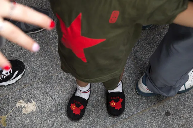 A child wears a pair of shoes embroidered with the map of China in the color of the national flag and the slogan “Those who invade my territory will be punished no matter how far away” as he lines up to visit an exhibition to mark the 90th anniversary of the founding of the People's Liberation Army at the military museum in Beijing, China, Tuesday, August 1, 2017. Chinese President Xi Jinping issued a tough line on national sovereignty Tuesday amid multiple territorial disputes with his country's neighbors, saying China will never permit the loss of “any piece” of its land to outsiders. (Photo by Ng Han Guan/AP Photo)