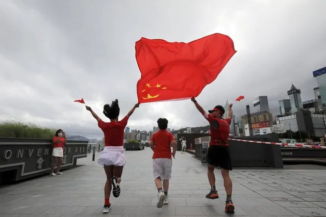 Supporters pose with Chinese and Hong Kong flags at the Convention Avenue, on the 25th anniversary of the former British colony's handover to Chinese rule, in Hong Kong, China on July 1, 2022. (Photo by Paul Yeung/Reuters)