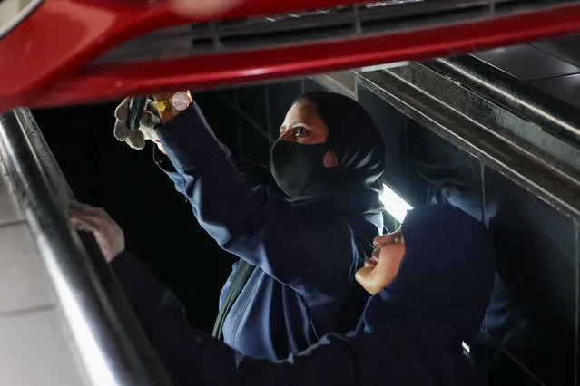 A picture taken May 26, 2022 shows Ghada Ahmed (L) and Ola Flimban working on a car at an auto quick service garage in Jeddah City. An auto repair garage in Saudi Arabia is turning to an untapped source for new mechanics: Saudi women, who just four years ago weren't even allowed to drive. At the Petromin Express garage in Jeddah, on the Red Sea coast, new female recruits check oil and change tires alongside their male counterparts, part of a nationwide push to bring more women into the workforce. (Photo by Fayez Nureldine/AFP Photo)