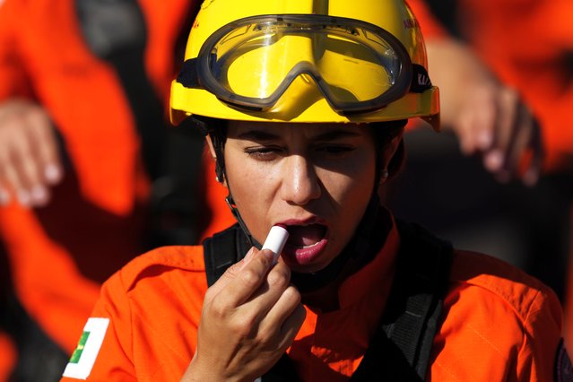 A member of the Military Fire Battalion applies lipstick before parading at a military parade on Independence Day in Brasilia, Brazil, Thursday, September 7, 2023. (Photo by Eraldo Peres/AP Photo)